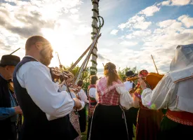 Folk danser og leker rundt midtsommerbaren.