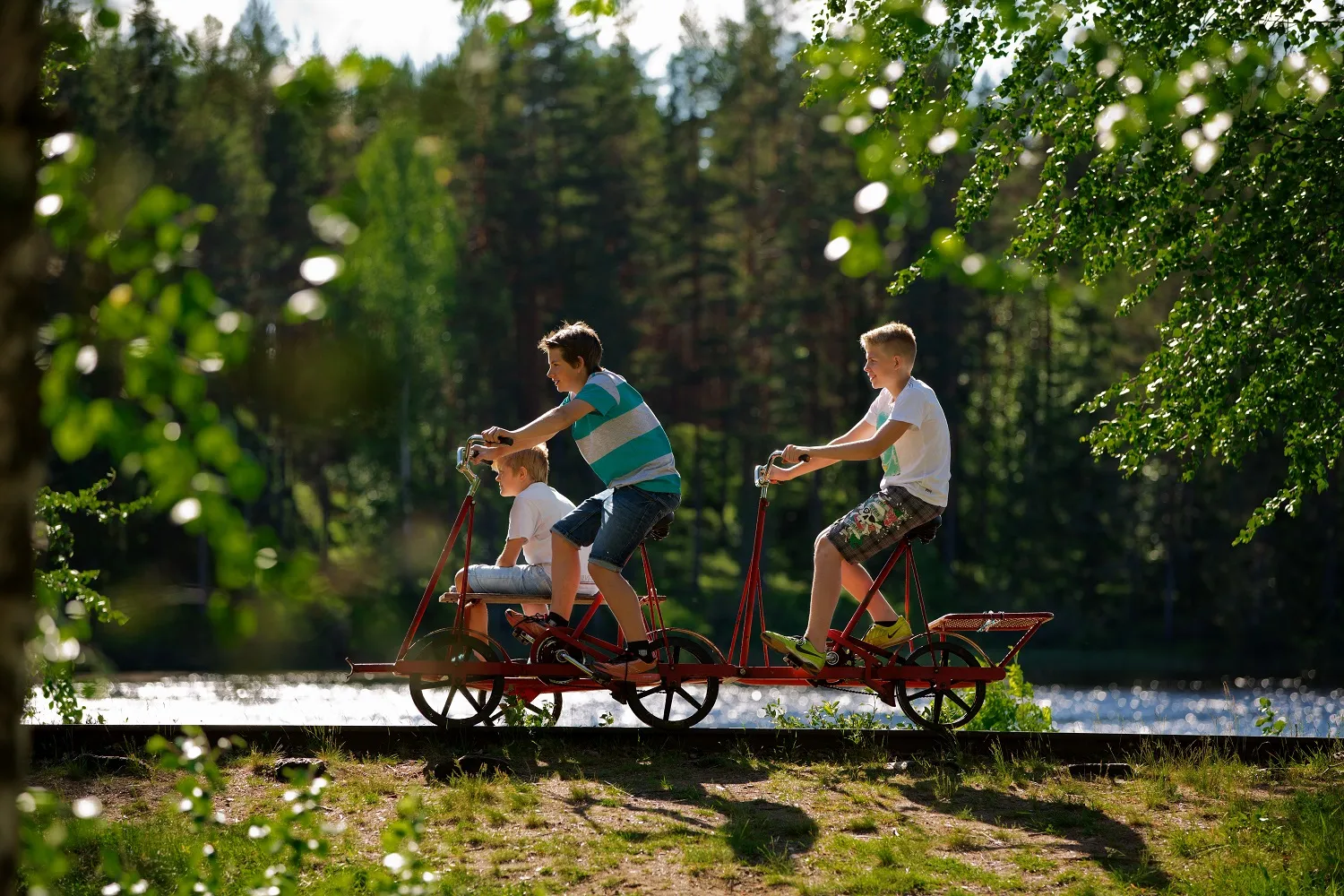 Tre gutter på en dresinsykkel ved vannet i Vansbro