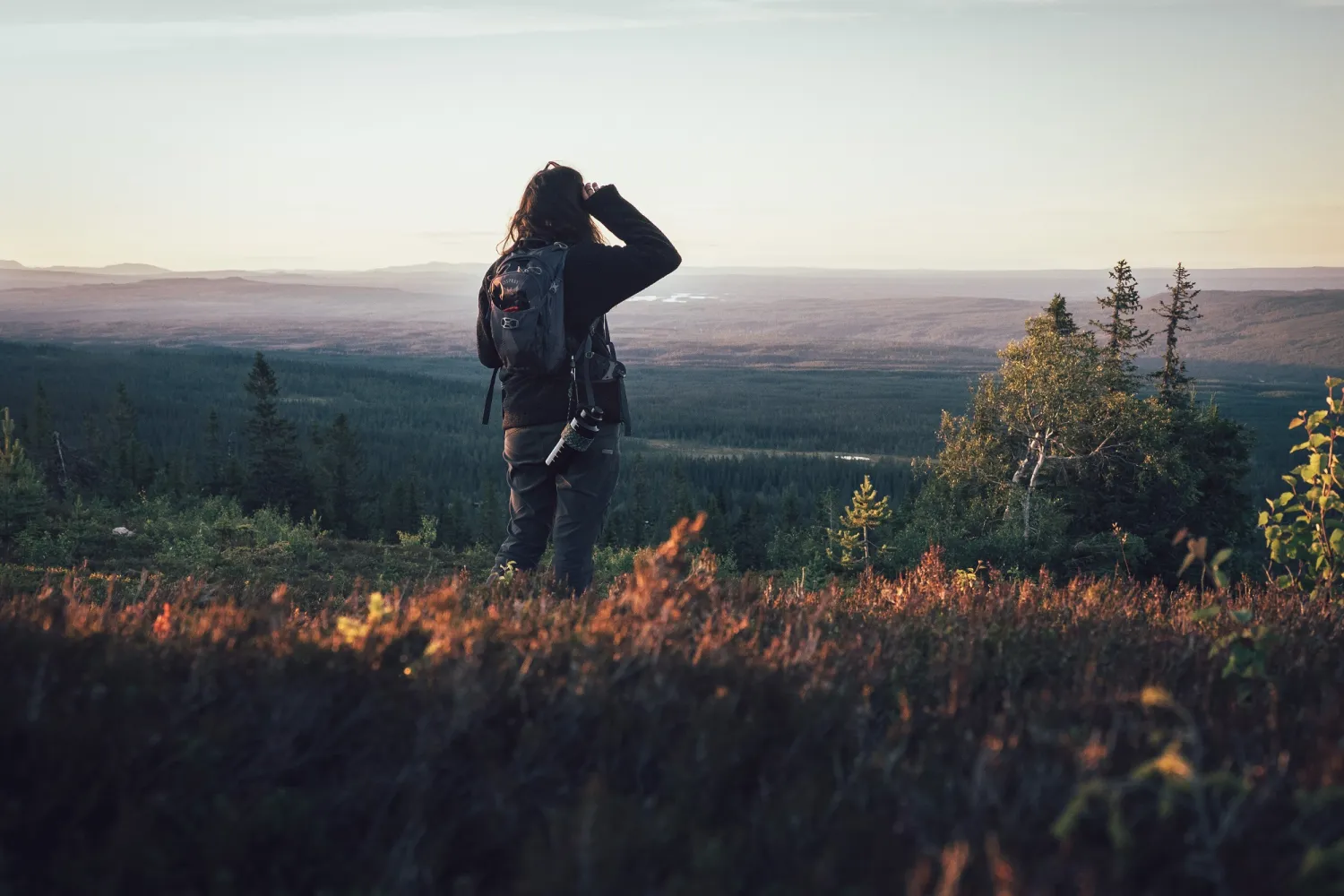 Een vrouw in een heuvelachtig landschap tuurt in de verte.