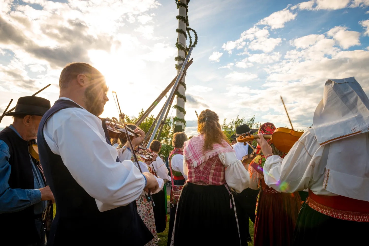 Folk danser og leker rundt midtsommerbaren.