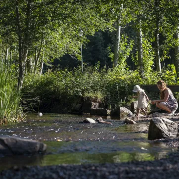 Ein Kind und ein Erwachsener spielen am Wasser.