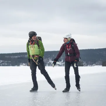 Een man en vrouw met helm op schaatsen op langeafstandschaatsen op natuurijs